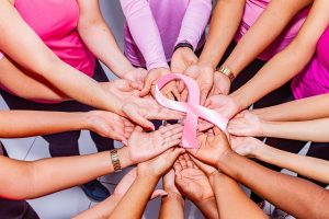 women holding hands with breast cancer bow