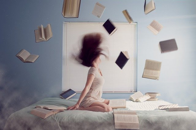 WOMAN ON BED WITH BOOKS FLYING AROUND