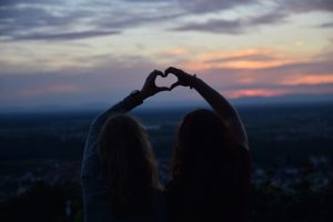 2 women doing heart sign with hand